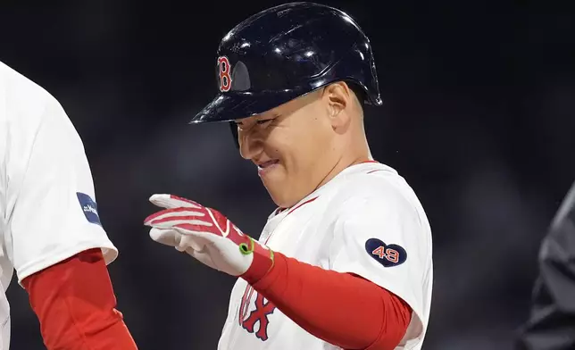 Boston Red Sox's Masataka Yoshida reacts in front of first base coach Andy Fox, left, after hitting a single during the third inning of a baseball game against the Chicago Cubs, Sunday, April 28, 2024, in Boston. (AP Photo/Michael Dwyer)