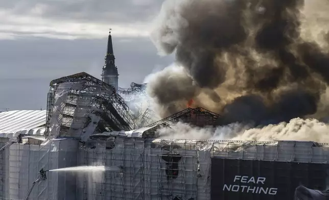 Firefighters work as smoke rises out of the Old Stock Exchange in Copenhagen, Denmark, Tuesday, April 16, 2024. A fire raged through one of Copenhagen’s oldest buildings on Tuesday, causing the collapse of the iconic spire of the 17th-century Old Stock Exchange as passersby rushed to help emergency services save priceless paintings and other valuables. (Emil Nicolai Helms/Ritzau Scanpix via AP)