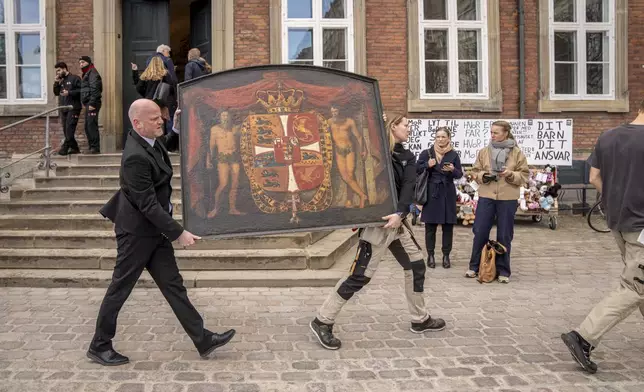 Historical paintings are carried out of the burning building as the Stock Exchange burns in Copenhagen, Denmark, Tuesday, April 16, 2024. A fire raged through one of Copenhagen’s oldest buildings on Tuesday, causing the collapse of the iconic spire of the 17th-century Old Stock Exchange as passersby rushed to help emergency services save priceless paintings and other valuables. (Ida Marie Odgaard/Ritzau Scanpix via AP)