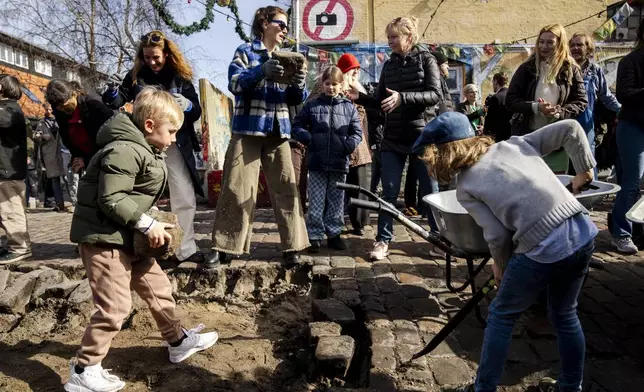 Citizens of the free village Christiania jointly dig up the cobblestones at Pusher Street, in Copenhagen, Denmark, Saturday April 6, 2024. After the cobblestones are removed, new water pipes and a new pavement will be laid on Pusher Street and nearby buildings will be renovated. That is the first step in an overall plan to turn the hippie oasis into an integrated part of the Danish capital area, although “the free state" spirit of creativity and community life is to be maintained. (Ida Marie Odgaard/Ritzau Scanpix via AP)