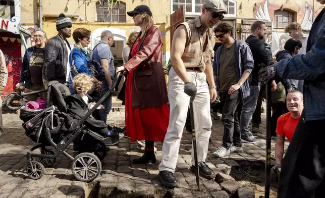 Citizens of the free village Christiania jointly dig up the cobblestones at Pusher Street, in Copenhagen, Denmark, Saturday April 6, 2024. After the cobblestones are removed, new water pipes and a new pavement will be laid on Pusher Street and nearby buildings will be renovated. That is the first step in an overall plan to turn the hippie oasis into an integrated part of the Danish capital area, although “the free state" spirit of creativity and community life is to be maintained. (Ida Marie Odgaard/Ritzau Scanpix via AP)