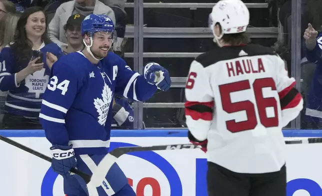 Toronto Maple Leafs center Auston Matthews, left, celebrates a goal, as New Jersey Devils left wing Erik Haula (56) skates nearby during the first period of an NHL hockey game Thursday, April 11, 2024, in Toronto. (Nathan Denette/The Canadian Press via AP)