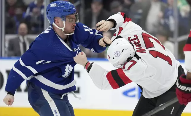 Toronto Maple Leafs center Max Domi (11) and New Jersey Devils defenseman Simon Nemec (17) fight during the second period of an NHL hockey game Thursday, April 11, 2024, in Toronto. (Nathan Denette/The Canadian Press via AP)