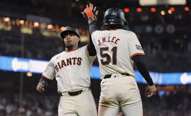San Francisco Giants' LaMonte Wade Jr., left, and Jung Hoo Lee celebrate after scoring against the Arizona Diamondbacks on Wilmer Flores' double during the eighth inning of a baseball game Thursday, April 18, 2024, in San Francisco. (AP Photo/Godofredo A. Vásquez)