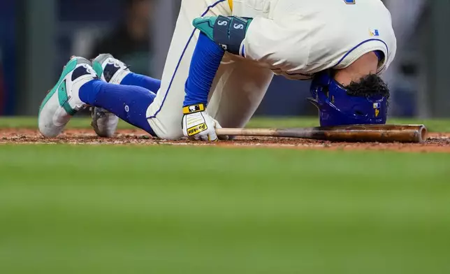 Seattle Mariners' Josh Rojas rests his head on the ground after fouling a ball off his foot against the Arizona Diamondbacks during the fifth inning of a baseball game Sunday, April 28, 2024, in Seattle. (AP Photo/Lindsey Wasson)