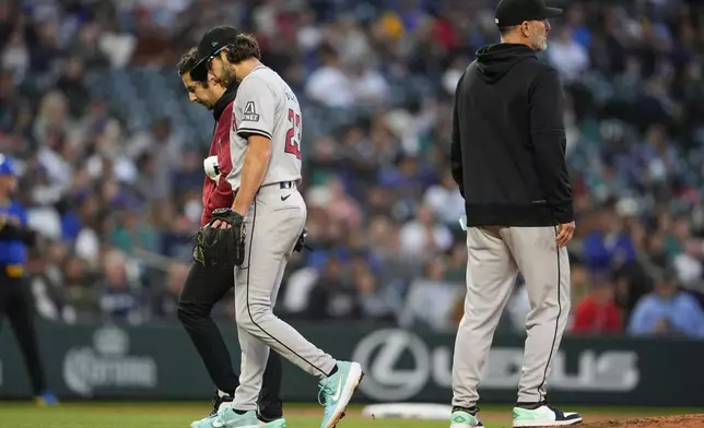 Arizona Diamondbacks starting pitcher Zac Gallen leaves with a trainer as manager Torey Lovullo, right, stands on the mound during the sixth inning of the team's baseball game against the Seattle Mariners, Friday, April 26, 2024, in Seattle. (AP Photo/Lindsey Wasson)