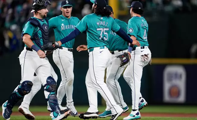 Seattle Mariners relief pitcher Andrés Muñoz (75), catcher Cal Raleight, left, and teammates celebrate a 3-1 win over the Arizona Diamondbacks in a baseball game Saturday, April 27, 2024, in Seattle. (AP Photo/Lindsey Wasson)