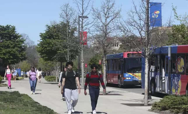 Students walk down Jayhawk Boulevard, the main street through the main University of Kansas campus, Friday, April 12, 2024, in Lawrence, Kan. The Kansas Board of Regents, which oversees higher education, has drafted a new policy against requiring diversity, equity and inclusion statements on applications for students, job seekers and staff promotions. (AP Photo/John Hanna)