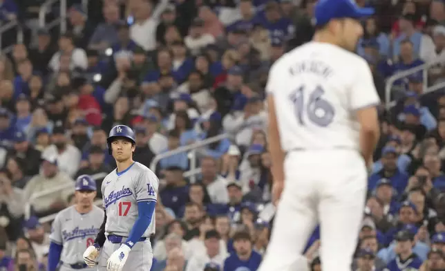 Los Angeles Dodgers' Shohei Ohtani looks over at Toronto Blue Jays pitcher Yusei Kikuchi as he stands on first base after hitting an RBI single during the second inning of a baseball game in Toronto, Saturday, April 27, 2024. (Chris Young/The Canadian Press via AP)