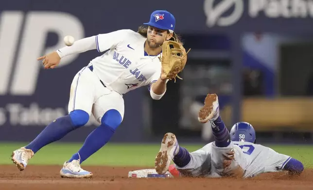 Los Angeles Dodgers' Mookie Betts steals second base in front of Toronto Blue Jays shortstop Bo Bichette during the ninth inning of a baseball game in Toronto, Saturday, April 27, 2024. (Chris Young/The Canadian Press via AP)