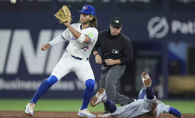 Los Angeles Dodgers' Mookie Betts (50) steals second base past as Toronto Blue Jays shortstop Bo Bichette waits for the throw during the third inning of a baseball game Friday, April 26, 2024, in Toronto. (Nathan Denette/The Canadian Press via AP)