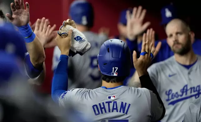 Los Angeles Dodgers' Shohei Ohtani (17) high fives teammates after scoring on a ground rule double hit by Teoscar Hernández during the fifth inning of a baseball game against the Arizona Diamondbacks, Monday, April 29, 2024, in Phoenix. (AP Photo/Matt York)