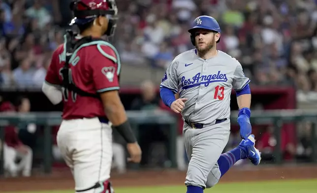 Los Angeles Dodgers' Max Muncy (13) scores on a sacrifice fly hit by Andy Pages during the second inning of a baseball game against the Arizona Diamondbacks, Monday, April 29, 2024, in Phoenix. (AP Photo/Matt York)