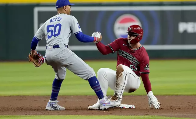 Los Angeles Dodgers' Mookie Betts (50) helps Arizona Diamondbacks' Christian Walker up after Walker was forced out on a double play hit by Eugenio Suárez during the third inning of a baseball game, Monday, April 29, 2024, in Phoenix. (AP Photo/Matt York)