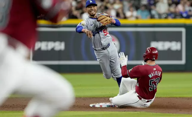 Los Angeles Dodgers' Mookie Betts (50) forces out Arizona Diamondbacks' Christian Walker as he turns a double play on Eugenio Suárez during the third inning of a baseball game, Monday, April 29, 2024, in Phoenix. (AP Photo/Matt York)