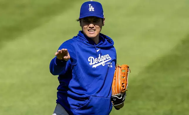 Los Angeles Dodgers' Shohei Ohtani reacts as he throws before a baseball game against the Washington Nationals at Nationals Park, Tuesday, April 23, 2024, in Washington. (AP Photo/Alex Brandon)