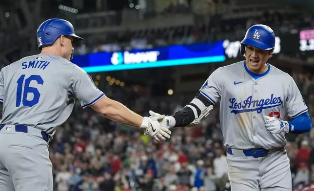 Los Angeles Dodgers designated hitter Shohei Ohtani, right, celebrates his solo home run with Will Smith during the ninth inning of a baseball game against the Washington Nationals at Nationals Park, Tuesday, April 23, 2024, in Washington. The Dodgers won 4-1. (AP Photo/Alex Brandon)