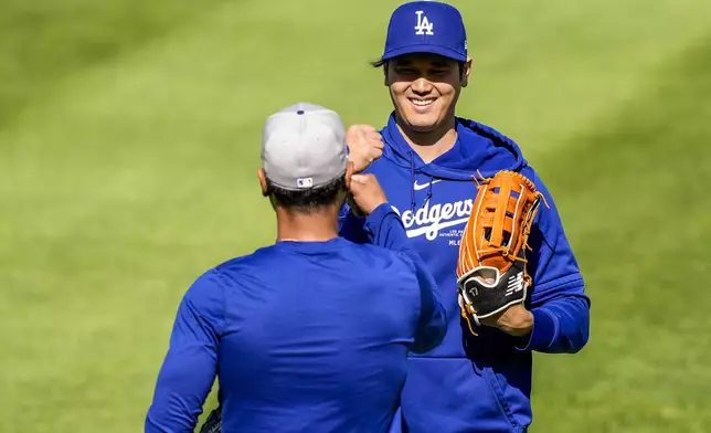 Los Angeles Dodgers' Shohei Ohtani reacts with his catcher after throwing before a baseball game against the Washington Nationals at Nationals Park, Tuesday, April 23, 2024, in Washington. (AP Photo/Alex Brandon)
