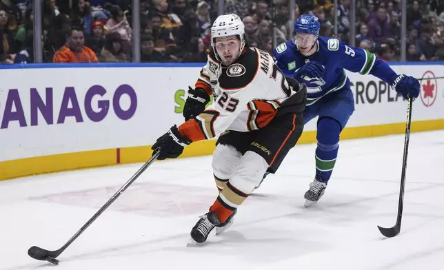 Anaheim Ducks' Mason McTavish (23) passes the puck as Vancouver Canucks' Tyler Myers (57) skates behind him during the second period of an NHL hockey game Sunday, March 31, 2024, in Vancouver, British Columbia. (Darryl Dyck/The Canadian Press via AP)