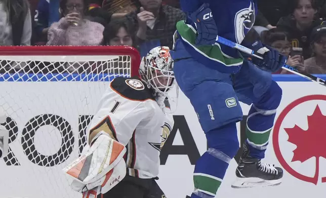 Anaheim Ducks goalie Lukas Dostal (1) makes a save as Vancouver Canucks' Dakota Joshua (81) jumps in front of him during the first period of an NHL hockey game Sunday, March 31, 2024, in Vancouver, British Columbia. (Darryl Dyck/The Canadian Press via AP)