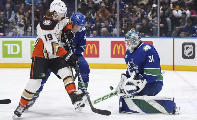 Vancouver Canucks goalie Arturs Silovs (31) makes a save as Tyler Myers (57) checks Anaheim Ducks' Troy Terry (19) during the first period of an NHL hockey game Sunday, March 31, 2024, in Vancouver, British Columbia. (Darryl Dyck/The Canadian Press via AP)