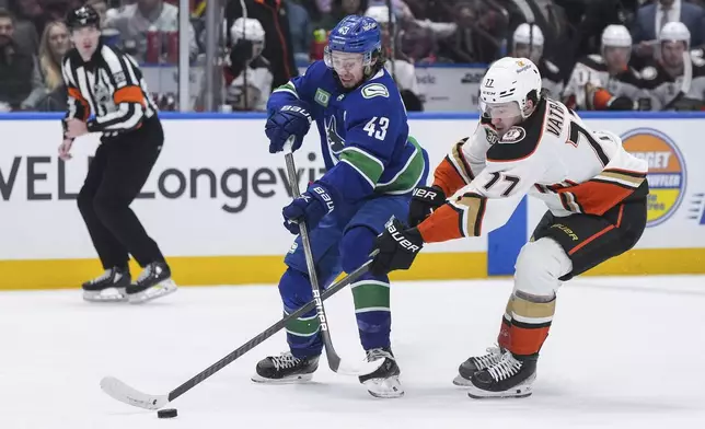 Vancouver Canucks' Quinn Hughes (43) and Anaheim Ducks' Frank Vatrano (77) vie for the puck during the second period of an NHL hockey game Sunday, March 31, 2024, in Vancouver, British Columbia. (Darryl Dyck/The Canadian Press via AP)