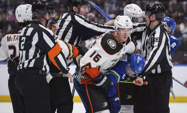 Anaheim Ducks' Ryan Strome (16) grabs Vancouver Canucks' Nils Hoglander (21) to pull him away from the scrum as linesmen Ryan Gibbons, back left, and Bevan Mills try to separate players during the third period of an NHL hockey game, in Vancouver, British Columbia, Sunday, March 31, 2024. (Darryl Dyck/The Canadian Press via AP)