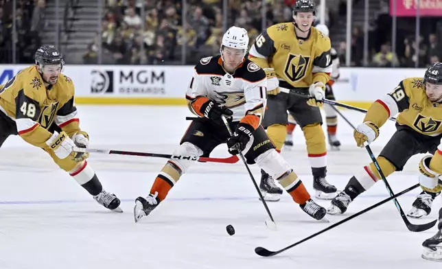 Anaheim Ducks center Trevor Zegras (11) skates with the puck between Vegas Golden Knights center Tomas Hertl (48), left wing Pavel Dorofeyev (16) and center Ivan Barbashev (49) during the first period of an NHL hockey game Thursday, April 18, 2024, in Las Vegas. (AP Photo/David Becker)