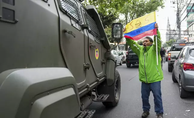 A supporter of former Ecuadorian Vice President Jorge Glas protests as a military vehicle transports him from the detention center he was held following his arrest at the Mexican Embassy in Quito Ecuador, Saturday, April 6, 2024. Glas, who held the vice presidency of Ecuador between 2013 and 2018, was convicted of corruption and had been taking refuge in the embassy since December. (AP Photo/Dolores Ochoa)