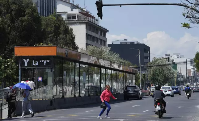 A woman runs across an avenue where traffic lights are not working due to a programed power cut ordered by the ministry of energy, in Quito, Ecuador, Tuesday, April 16, 2024. Ecuador faces electricity rationing due to a prolonged drought and high temperatures that have reduced flows to the main hydroelectric plants. (AP Photo/Dolores Ochoa)