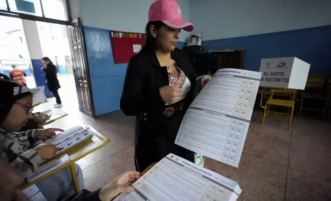 A woman holds the ballot to vote in a referendum proposed by President Daniel Noboa to endorse new security measures aimed at cracking down on criminal gangs fueling escalating violence, in Quito, Ecuador, Sunday, April 21, 2024. (AP Photo/Dolores Ochoa)