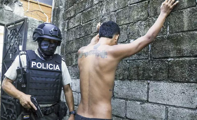 FILE - A resident stands with arms spread apart up against a wall as police search for weapons and or drugs, as part of an operation to combat criminal groups, in Guayaquil, Ecuador, April 4, 2024. Ecuadorians head to the polls Sunday, April 21, in a referendum touted by President Daniel Noboa as a way to crack down on criminal gangs behind a spiraling wave of violence. (AP Photo/Cesar Munoz, File)