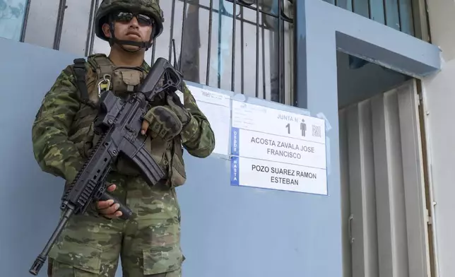 A soldier guars a pollen station during referendum proposed by President Daniel Noboa to endorse new security measures aimed at cracking down on criminal gangs fueling escalating violence, in Olon, Ecuador, Sunday, April 21, 2024. (AP Photo/Cesar Munoz)