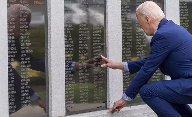 President Joe Biden reaches to touch the name of his uncle Ambrose J. Finnegan, Jr., on a wall at a Scranton war memorial, Wednesday, April 17, 2024, in Scranton, Pa. His uncle died in WWII. (AP Photo/Alex Brandon)