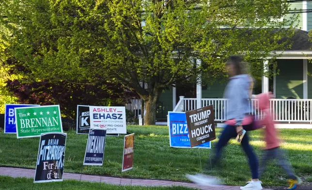 A voter and child walk past campaign signs posted outside of a polling site in Doylestown, Pa., Tuesday, April 23, 2024. (AP Photo/Matt Rourke)