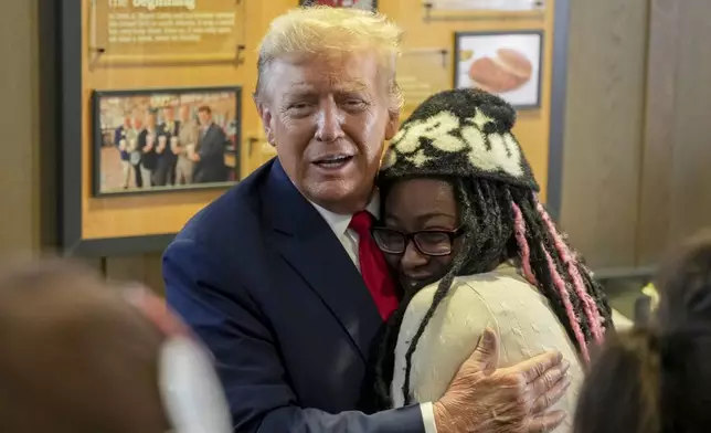 Republican presidential candidate former President Donald Trump, left, hugs Michaelah Montgomery, a local conservative activist, as he visits a Chick-fil-A eatery, Wednesday, April 10, 2024, in Atlanta. (AP Photo/Jason Allen)