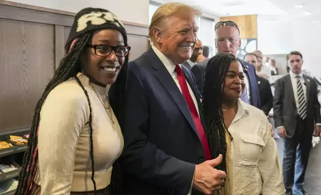 Republican presidential candidate former President Donald Trump, center, takes a photo with Michaelah Montgomery, left, a local conservative activist, as he visits a Chick-fil-A eatery, Wednesday, April 10, 2024, in Atlanta. (AP Photo/Jason Allen)