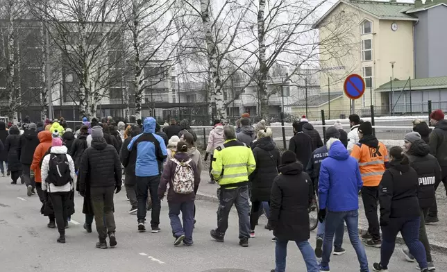 Police officers lead family members of pupils of the Viertola comprehensive school before entering the school, in Vantaa, Finland, Tuesday, April 2, 2024. A 12-year-old student opened fire at a secondary school in southern Finland on Tuesday morning, killing one and seriously wounded two other students, police said. The suspect was later arrested. (Markku Ulander/Lehtikuva via AP)