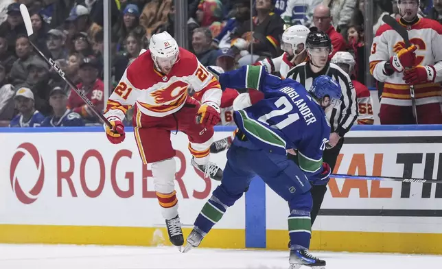 Calgary Flames' Kevin Rooney, left, and Vancouver Canucks' Nils Hoglander collide during the third period of an NHL hockey game Tuesday, April 16, 2024, in Vancouver, British Columbia. (Darryl Dyck/The Canadian Press via AP)