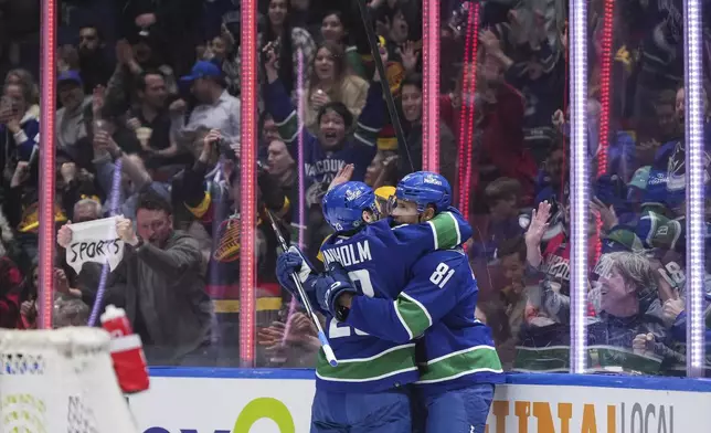 Vancouver Canucks' Dakota Joshua, right, and Elias Lindholm celebrate Joshua's goal against the Calgary Flames during the second period of an NHL hockey game Tuesday, April 16, 2024, in Vancouver, British Columbia. (Darryl Dyck/The Canadian Press via AP)