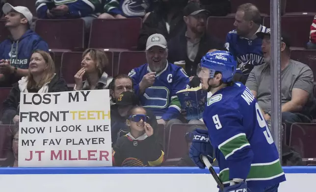 A young fan holds a sign as Vancouver Canucks' J.T. Miller skates past before during the second period of the team's NHL hockey game against the Calgary Flames on Tuesday, April 16, 2024, in Vancouver, British Columbia. (Darryl Dyck/The Canadian Press via AP)