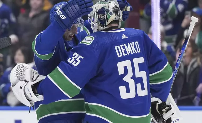 Vancouver Canucks' Ilya Mikheyev, left, and goalie Thatcher Demko celebrate the team's win over the Calgary Flames in an NHL hockey game Tuesday, April 16, 2024, in Vancouver, British Columbia. (Darryl Dyck/The Canadian Press via AP)