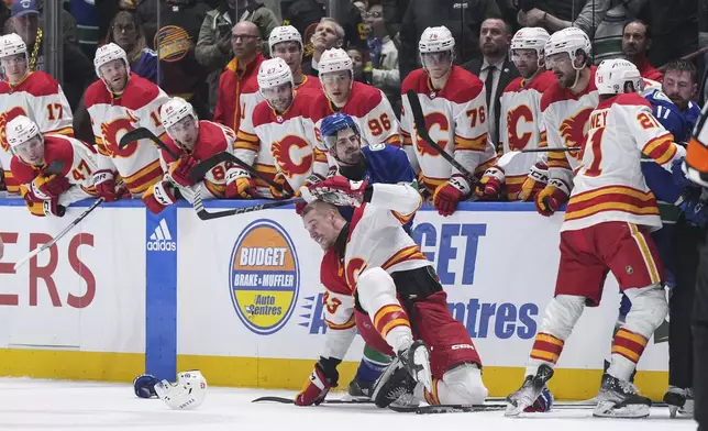 Vancouver Canucks' Conor Garland, back, grabs Calgary Flames' Adam Klapka as all the skaters on the ice get into a scuffle during the second period of an NHL hockey game Tuesday, April 16, 2024, in Vancouver, British Columbia. (Darryl Dyck/The Canadian Press via AP)