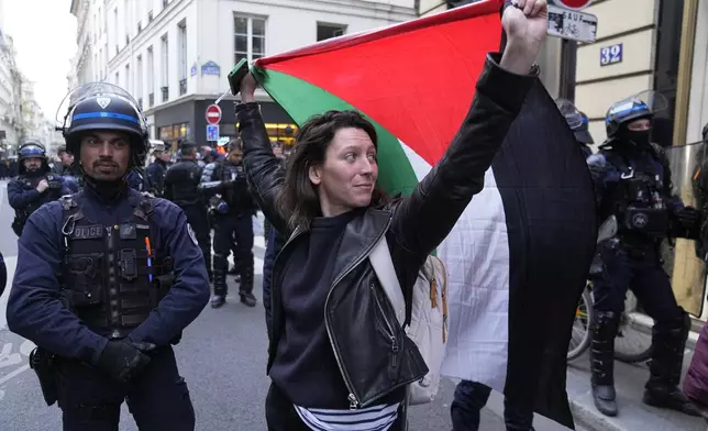A woman holds a Palestine flag near Sciences-Po university in Paris Friday, April 26, 2024. Students in Paris inspired by Gaza solidarity encampments at campuses in the United States blocked access to a campus building at a prestigious French university Friday, prompting administrators to move all classes online. The pro-Palestinian protest at the Paris Institute of Political Studies, known as Sciences Po, came two days after police broke up a separate demonstration at one of the university's amphitheaters. (AP Photo/Michel Euler)