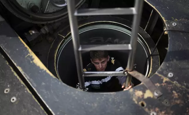 A sailor descends into a French Rubis-class submarine at the Toulon naval base in southern France, Monday, April 15, 2024. The nuclear powered submarine will be guarding France's Charles de Gaulle aircraft carrier during training exercises dubbed Neptune Strike in the Mediterranean with the 32-nation NATO military alliance. (AP Photo/Daniel Cole)