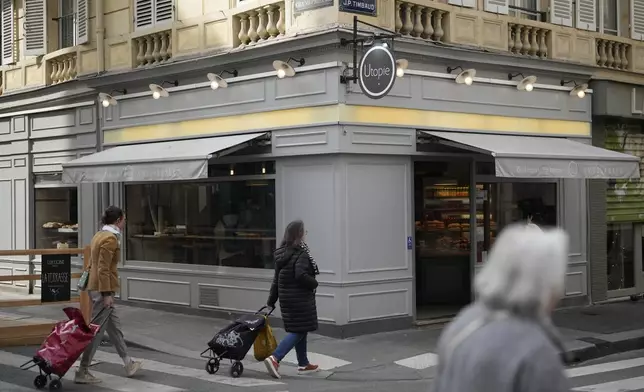 Parisians walk by the Utopie bakery Friday, April 26, 2024 in Paris. Baker Xavier Netry was chosen this week as the 31st winner of Paris' annual "Grand Prix de la baguette" prize. The Utopie bakery in Paris' 11th district that Netry works for wins 4,000 euros ($4,290) and becomes one of the suppliers of the presidential Elysee Palace for a year. (AP Photo/Thibault Camus)