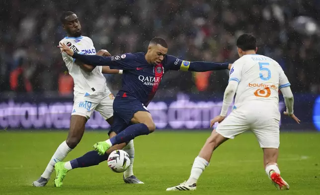 PSG's Kylian Mbappe, center, challenges with Marseille's Geoffrey Kondogbia, left, and Marseille's Leonardo Balerdi during the French League One soccer match between Marseille and Paris at the Velodrome stadium in Marseille, south of France, Sunday, March 31, 2024. (AP Photo/Daniel Cole)