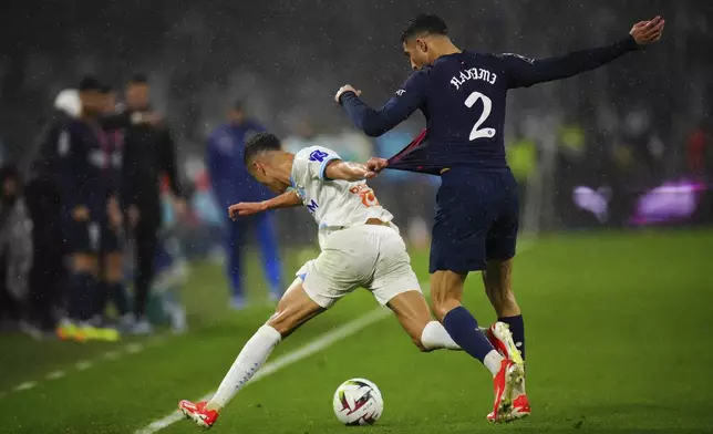 Marseille's Amine Harit, left, challenges for the ball with PSG's Achraf Hakimi during the French League One soccer match between Marseille and Paris at the Velodrome stadium in Marseille, south of France, Sunday, March 31, 2024. (AP Photo/Daniel Cole)