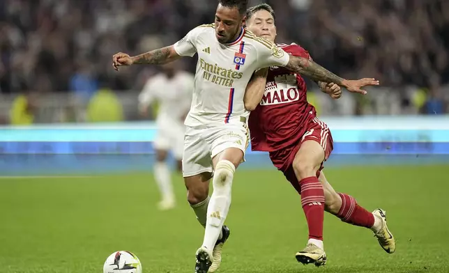 Brest's Martin Satriano, right, challenges Lyon's Corentin Tolisso during a French League One soccer match between Lyon and Brest at the Groupama stadium, outside Lyon, France, Sunday, April 14, 2024. (AP Photo/Laurent Cipriani)