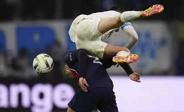 Marseille's Quentin Merlin jumps over PSG's Achraf Hakimi during the French League One soccer match between Marseille and Paris at the Velodrome stadium in Marseille, south of France, Sunday, March 31, 2024. (AP Photo/Daniel Cole)